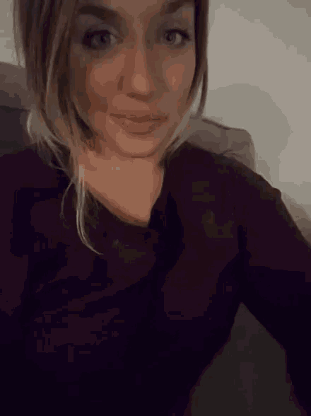 a woman in a purple shirt is sitting on a couch