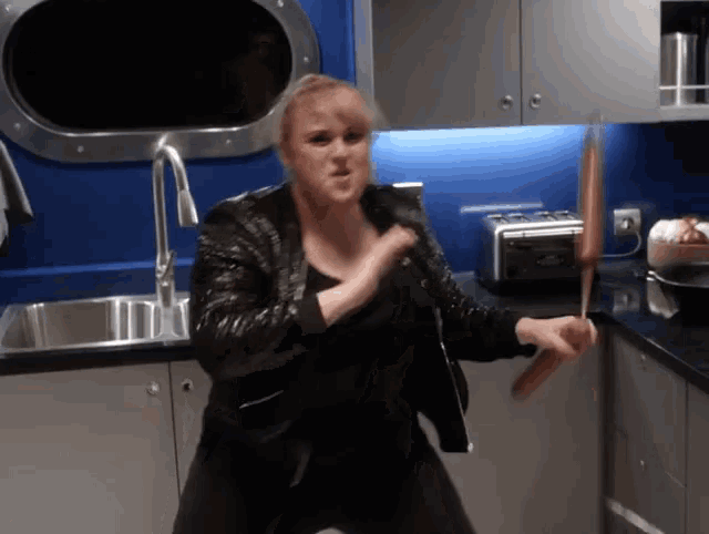 a woman in a leather jacket is holding a knife