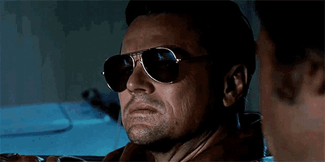 a man wearing sunglasses is looking at another man .