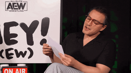 a man sitting in front of an aew sign