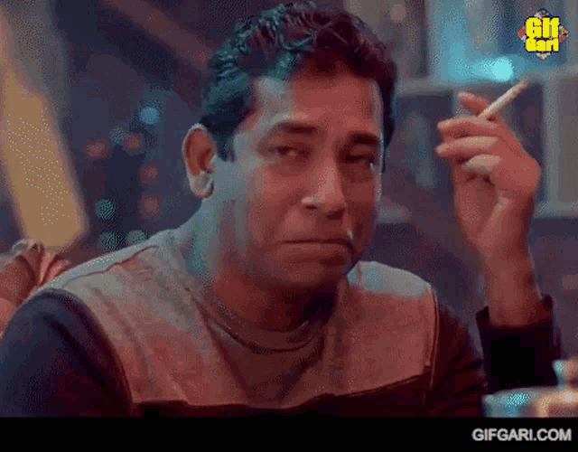 a man is smoking a cigarette in a dark room and making a funny face .