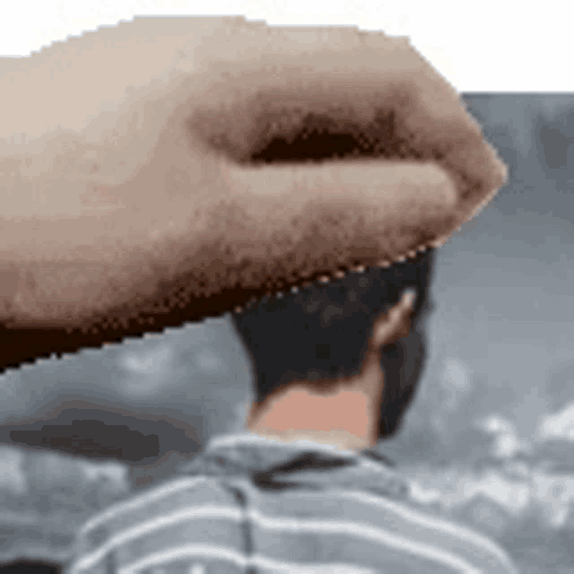a hand is holding a man 's head in front of a picture of a man 's back .