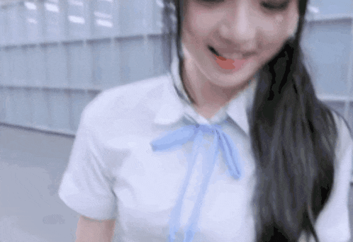 a woman in a school uniform with a blue bow is smiling .
