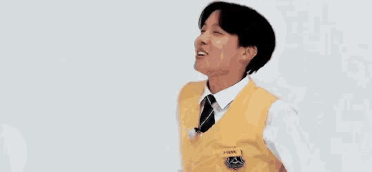 a young man wearing a yellow vest and tie is dancing .