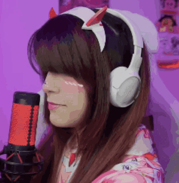 a woman wearing headphones and a headband with horns is standing in front of a microphone