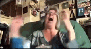 a woman is sitting on a couch with her mouth open and her hands up .