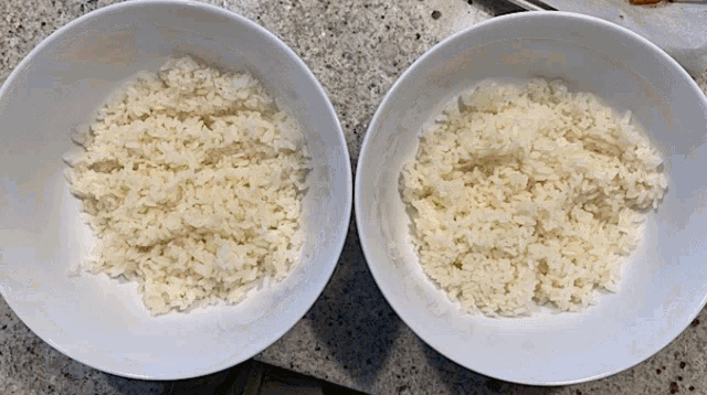 two bowls of white rice sit on a counter top