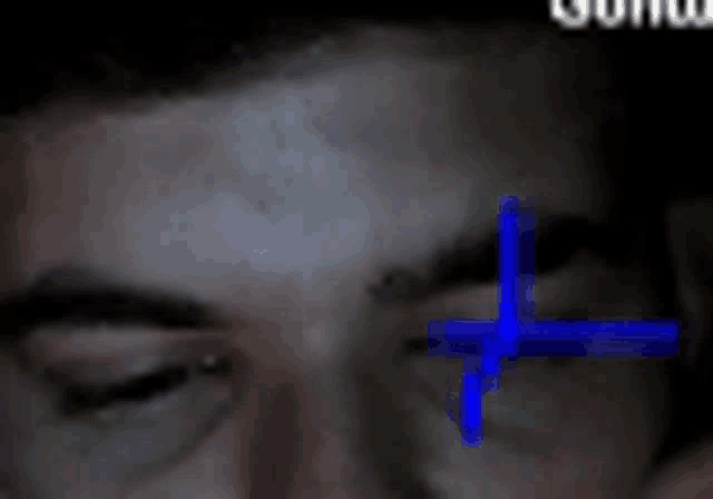 a close up of a man 's face with a blue cross in his eye