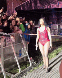 a woman in a red swimsuit is walking towards a crowd