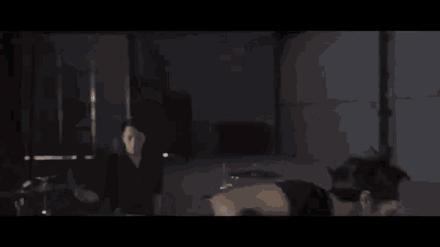 a man is playing a guitar in a dark room while another man kicks him .
