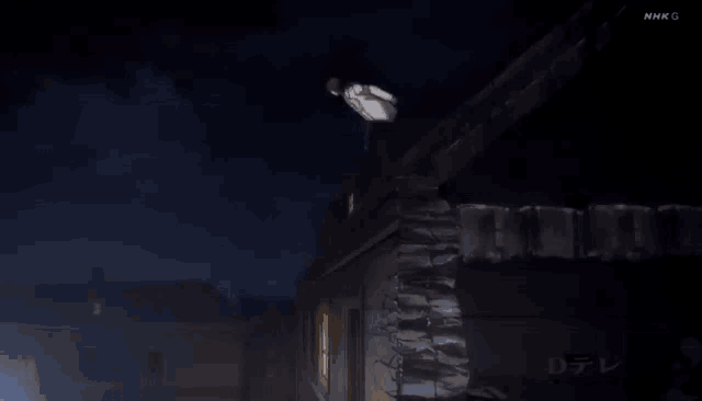 a man is jumping off the roof of a building at night .