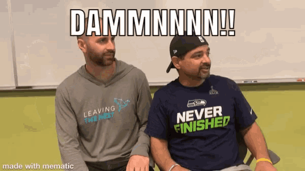 two men wearing shirts that say " never finished " are sitting next to each other