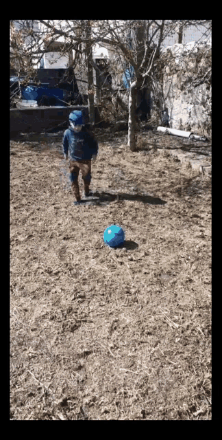 a child is kicking a blue ball in a field