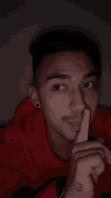a man with a tattoo on his wrist is holding his finger to his mouth .