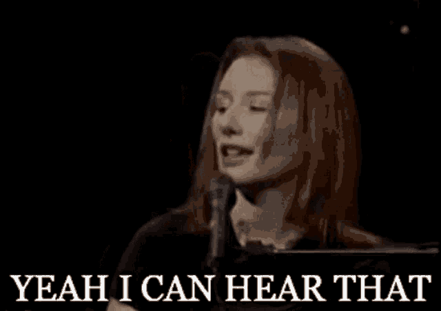 a woman singing into a microphone with the words yeah i can hear that behind her