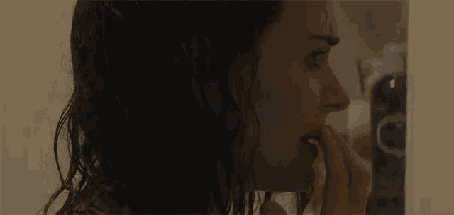 a woman with long hair is looking at herself in the mirror