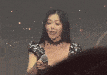 a woman is holding a microphone and talking into it while wearing a choker .