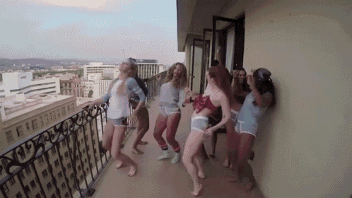 a group of women are dancing on a balcony overlooking a city .