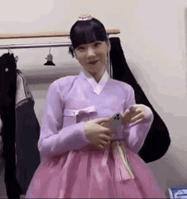 a woman in a pink dress is taking a picture of herself in a dressing room .