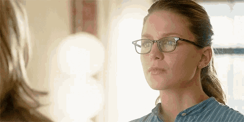 a woman wearing glasses and a striped shirt looks at another woman