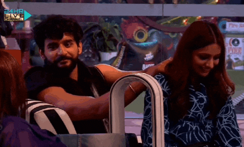 a man and a woman are sitting in front of a sign that says 24hr live