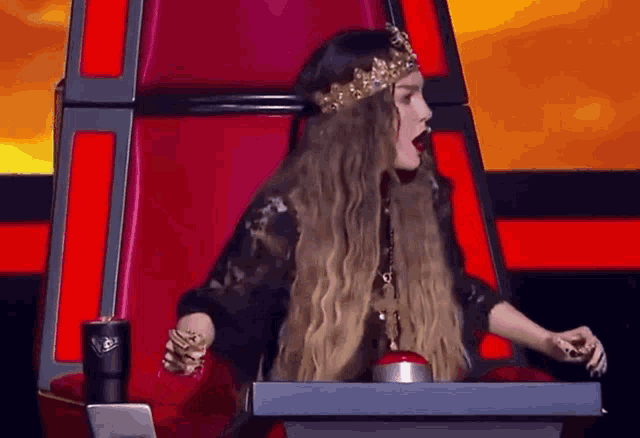 a woman with long hair and a crown on her head is sitting in a throne .