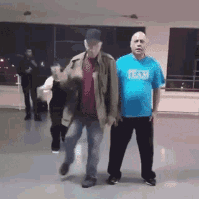 a man wearing a blue shirt that says team is walking with another man