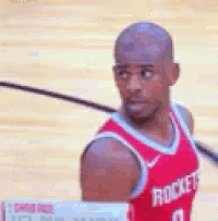 a man wearing a red rockets jersey is standing on a court .