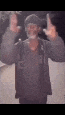 a man with a beard and glasses is giving the middle finger while wearing a hat .