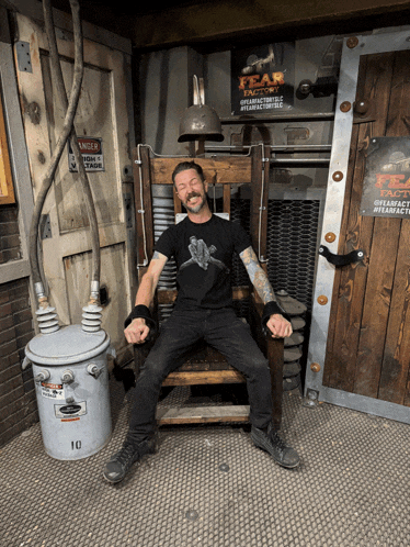 a man sits in a chair with a sign that says fear factory
