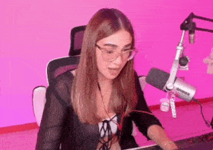 a woman wearing glasses is sitting in front of a microphone in a room .