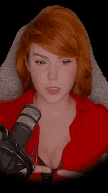 a woman with red hair is sitting in front of a microphone and headphones