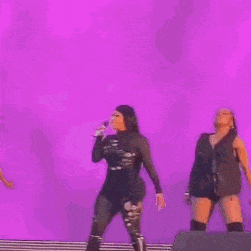 a woman is standing on a stage holding a microphone and dancing .