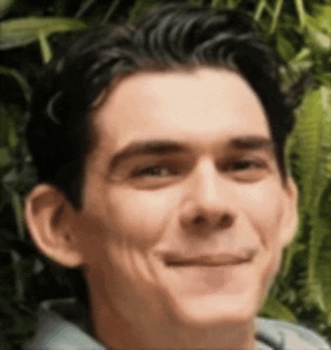 a close up of a man 's face smiling in front of a green background