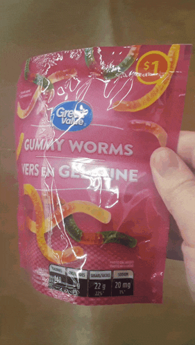 a person is holding a bag of gummy worms that cost $ 1