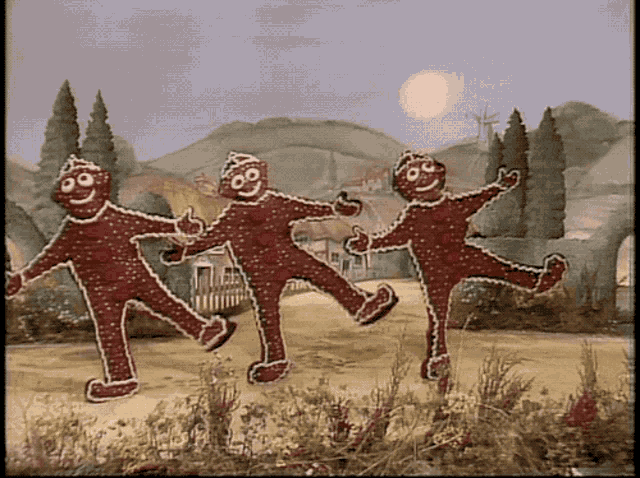 three gingerbread men are dancing in a field in front of a house