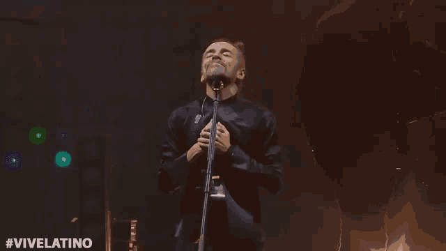 a man singing into a microphone with the hashtag #vivelatino