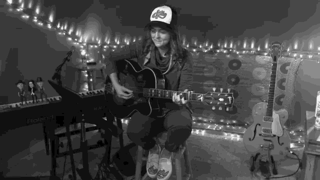a woman playing a guitar with a roland keyboard in the background