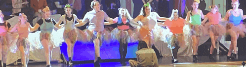 a group of people are dancing on a stage and a man is taking a picture