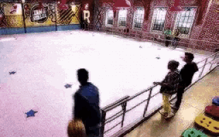 a group of people are standing in front of an ice rink .