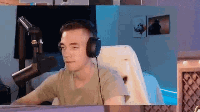 a man wearing headphones is sitting in front of a microphone and looking at the camera .