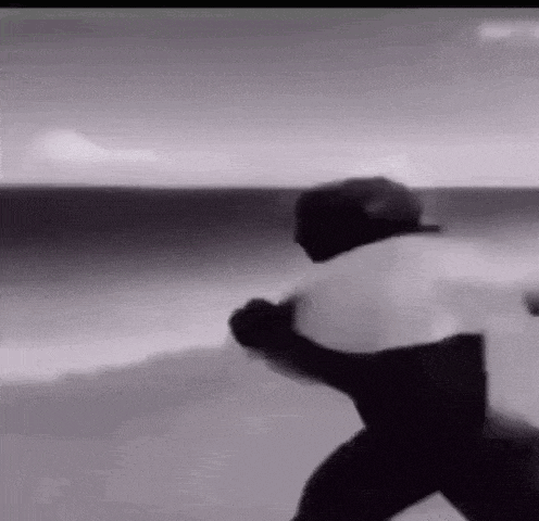 a black and white photo of a man standing on a beach .