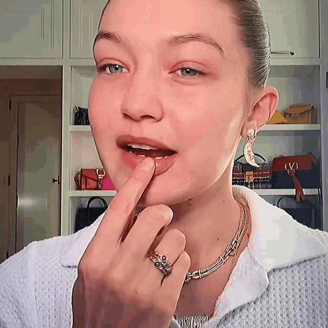 a woman wearing a necklace and a ring with a letter v on it