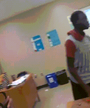 a blurry picture of a man in a classroom with a sign on the wall that says ' i '