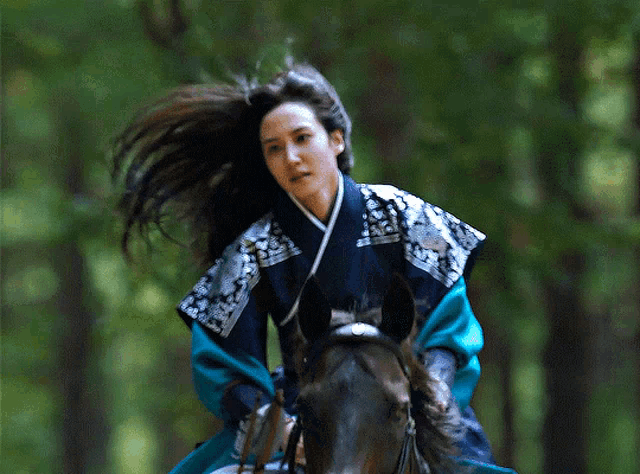 a woman is riding a horse in a forest