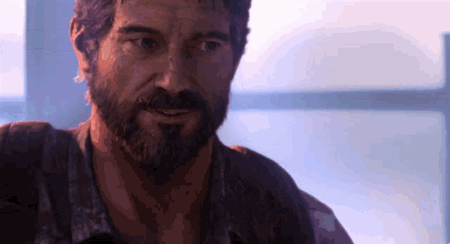 a man with a beard looks at the camera with a blurred background