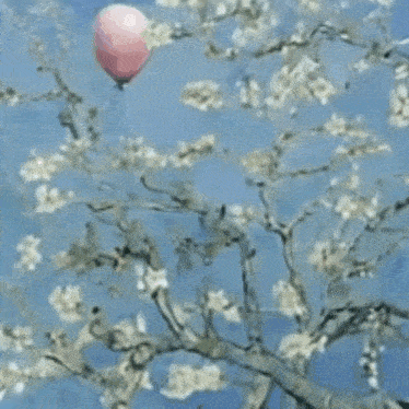 a pink balloon is flying over a tree with flowers