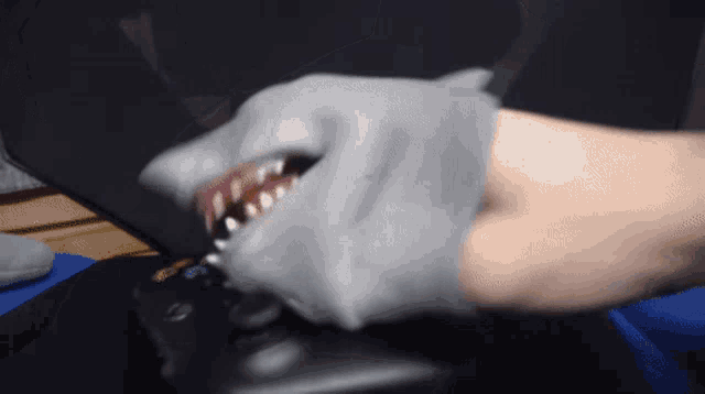 a person wearing a shark head glove is holding a remote control