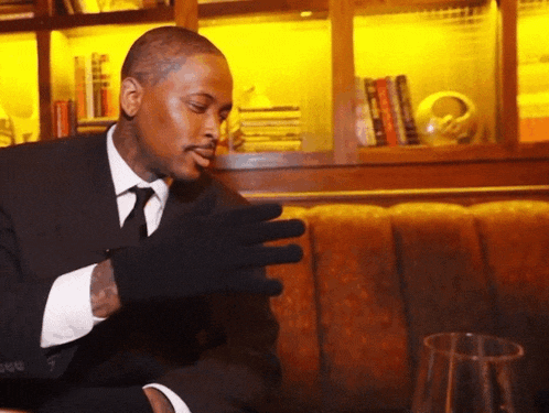 a man in a suit and tie is sitting on a couch wearing a black glove