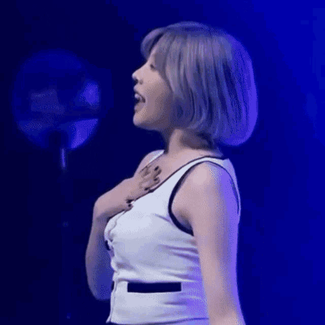 a woman with short gray hair is standing on a stage in front of a blue light .